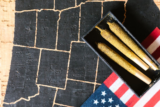 An American flag backdrop with three neatly rolled joints placed on it, symbolizing the intersection of cannabis culture and American identity.