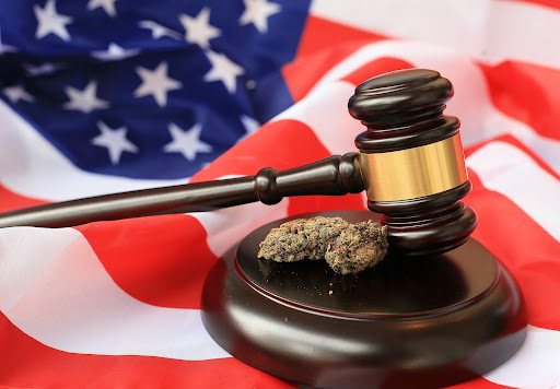 An American flag as the backdrop, adorned with a justice hammer and a marijuana leaf symbol, representing the intersection of legal, patriotic, and cannabis-related themes.